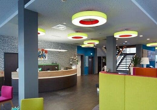 Modern lobby area with colorful ceiling lights and a reception desk.