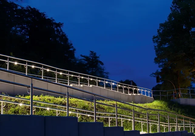 Illuminated terraced garden with railing lights at dusk.