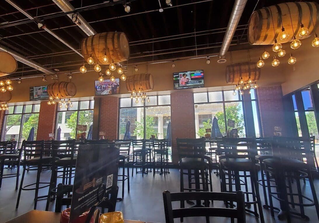 Spacious modern restaurant interior with large windows and hanging lights.