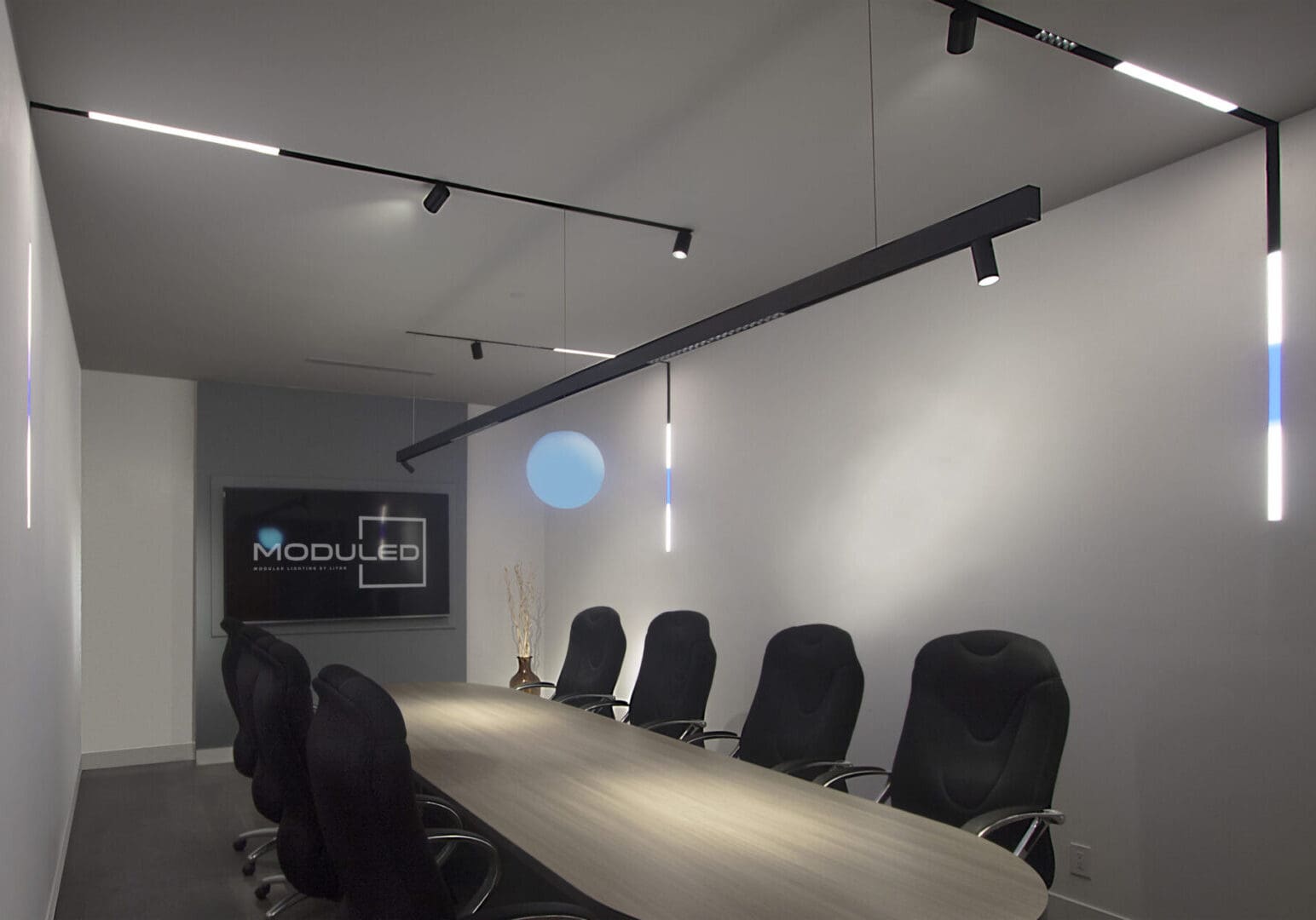 Modern conference room with black chairs and a large table under sleek lighting.