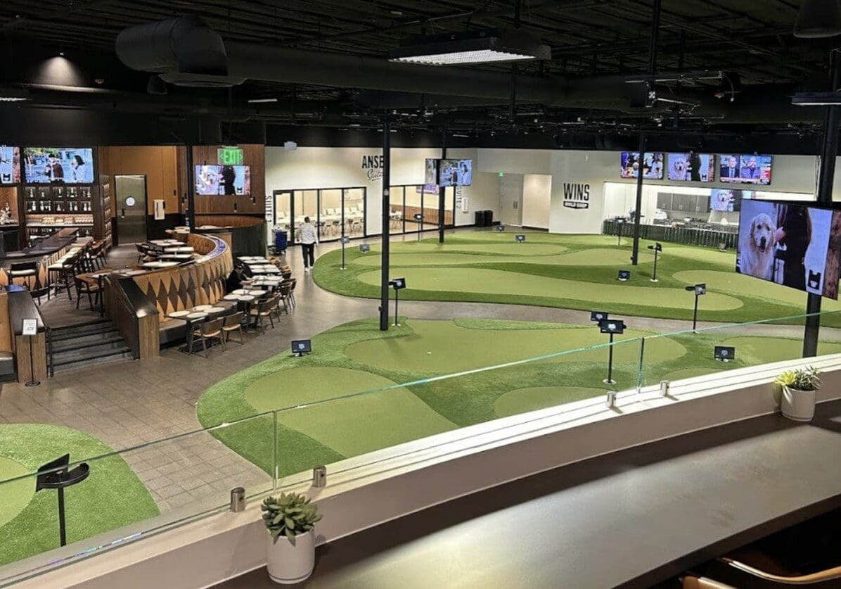 Indoor mini golf course with modern design and digital screens.