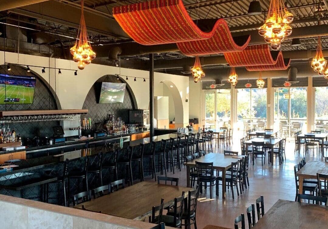 Cozy restaurant interior with wooden tables, chairs, and unique hanging lights.