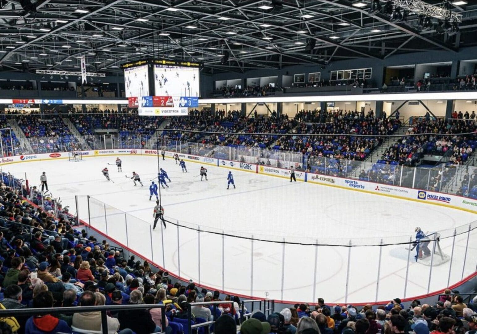 A packed ice hockey arena with players on the ice and fans watching.