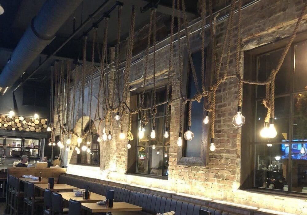 Cozy industrial-style cafe with warm hanging lights and brick walls.