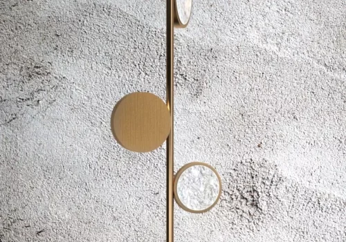 Modern gold wall decor with circular elements on textured gray wall.