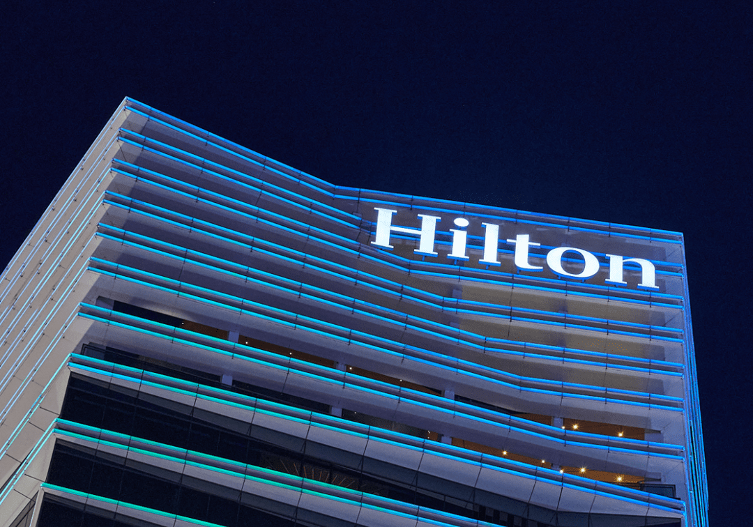 Night view of Hilton hotel building illuminated against the dark sky.
