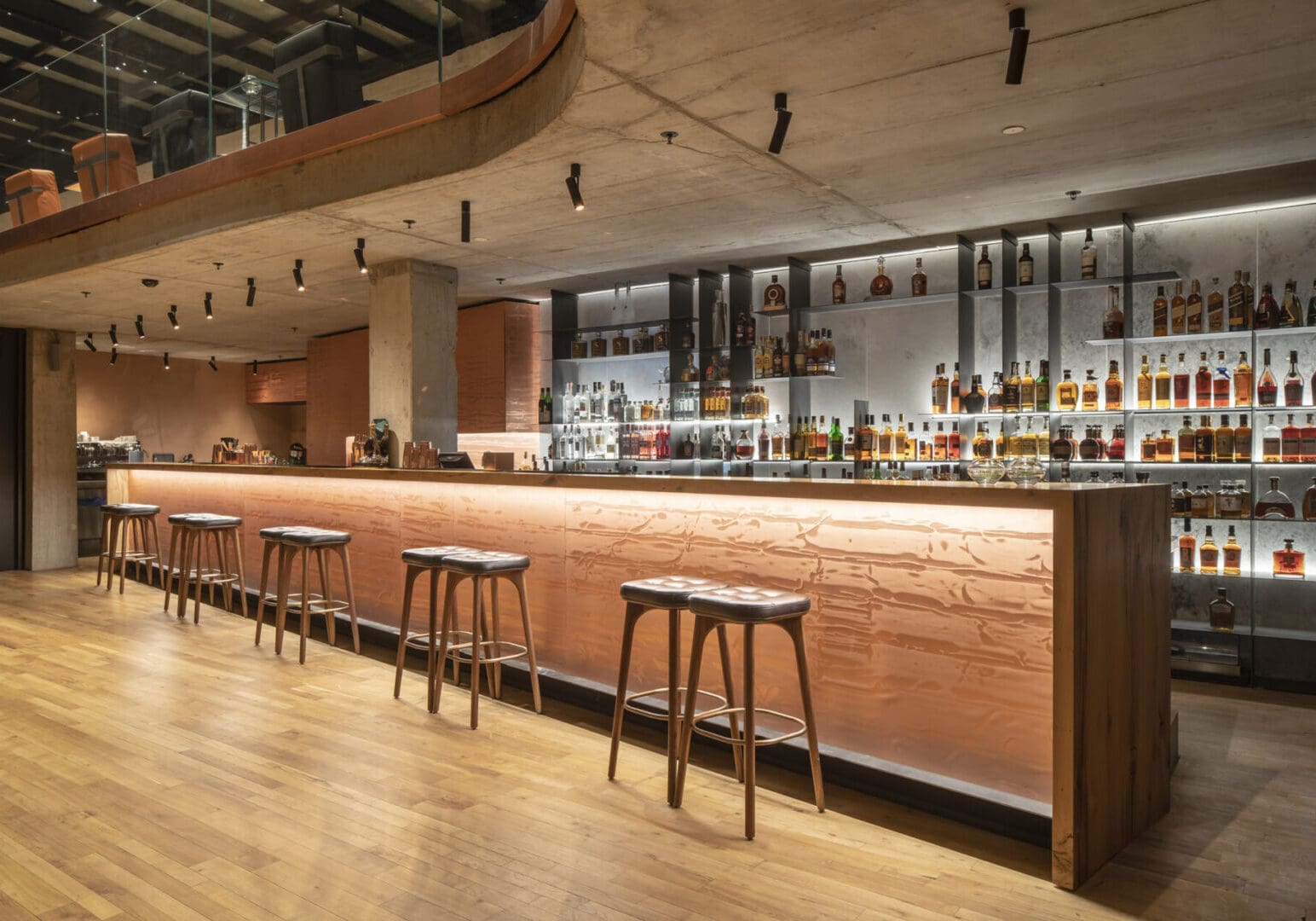 Modern bar with wooden stools and warm lighting.