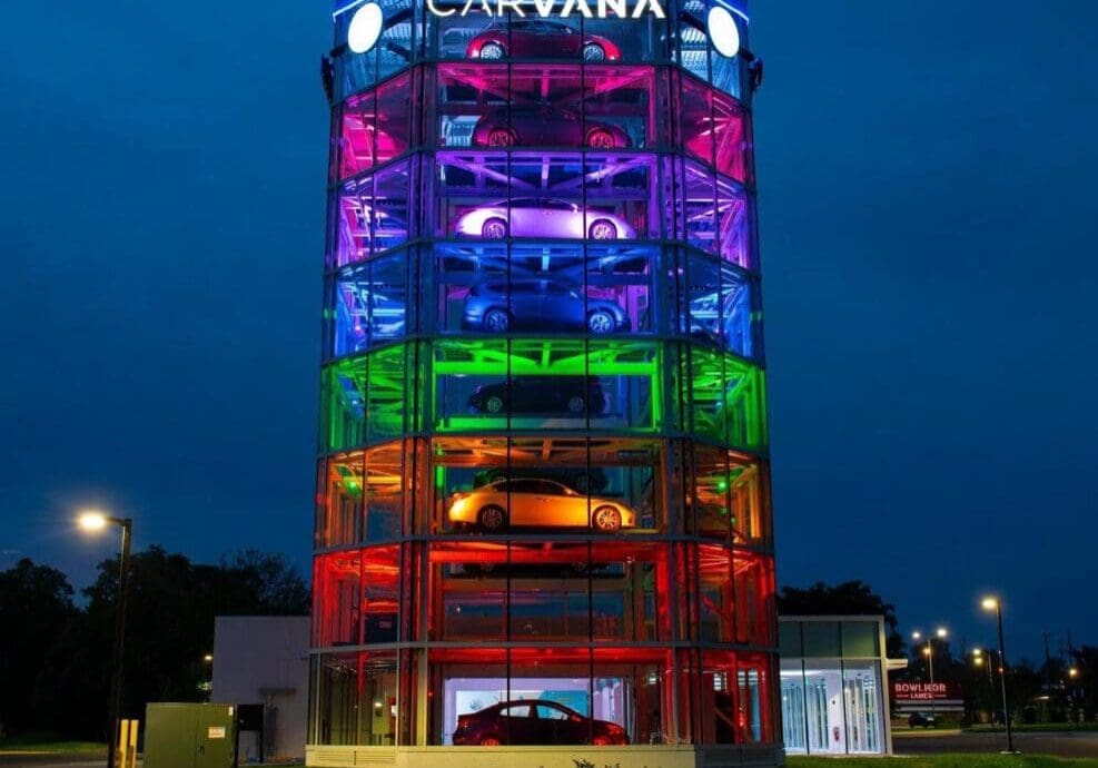 Colorfully illuminated multi-story cylindrical building at night.