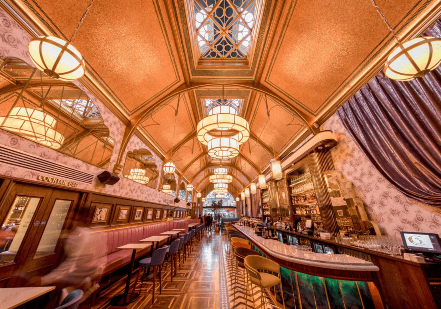 Elegant historic library interior with wooden arches and chandeliers.