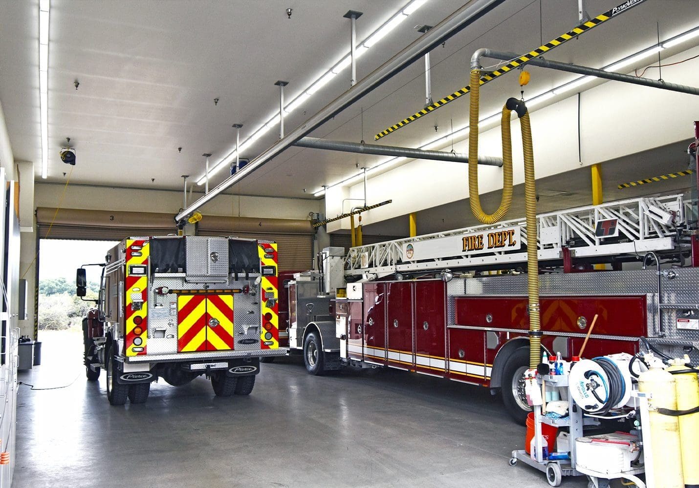 Two fire trucks parked inside a fire station garage.